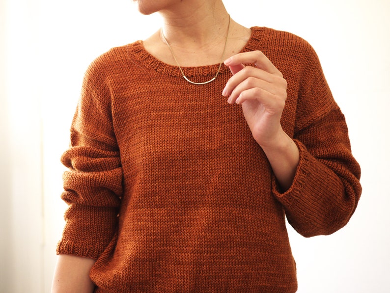May include: A brown knitted sweater with long sleeves and a round neckline.