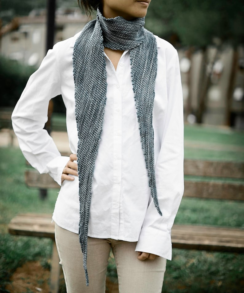 May include: A white button-down shirt with long sleeves and a blue and grey knitted scarf.