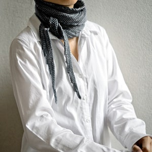 May include: A person wearing a white button-down shirt with a grey scarf tied around their neck.