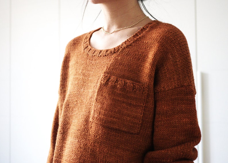 May include: A brown knitted sweater with a patch pocket on the front.