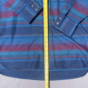 May include: A long-sleeved shirt with a blue, teal, and burgundy striped pattern. The shirt has a button-down front and cuffs. The shirt's length is approximately 34 inches.