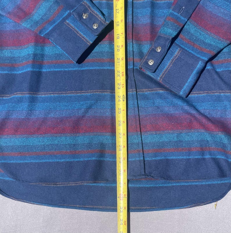 May include: A long-sleeved shirt with a blue, teal, and burgundy striped pattern. The shirt has a button-down front and cuffs. The shirt's length is approximately 34 inches.