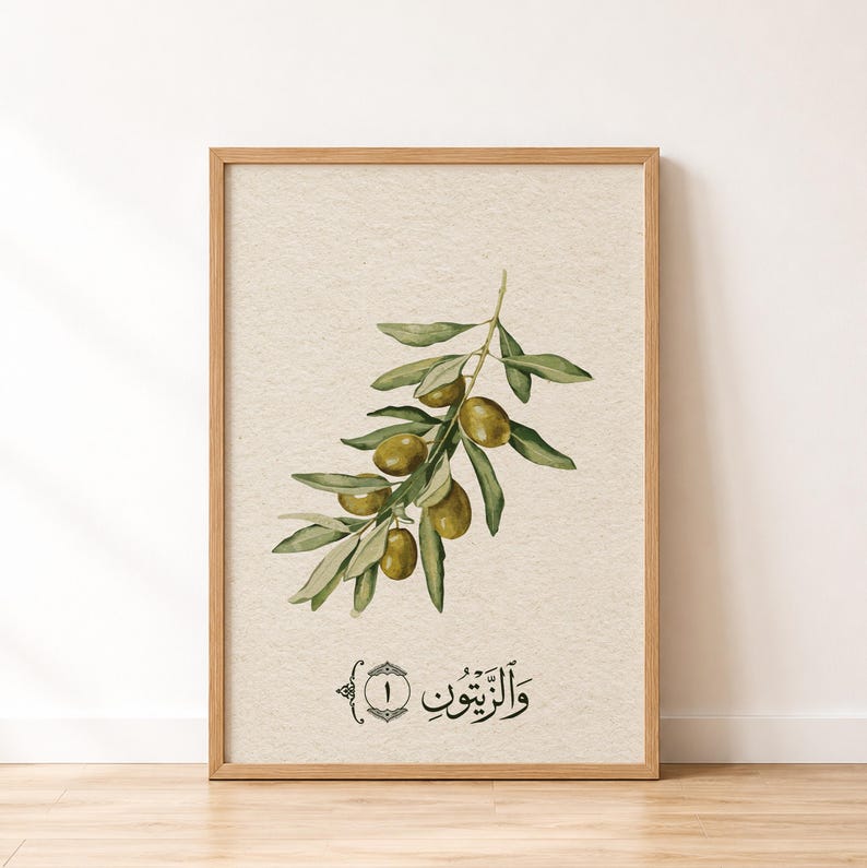 May include: A framed wall art print featuring a watercolor illustration of an olive branch with green leaves and olives on a textured beige background. Below the branch, the Arabic text "والزيتون" is written in black calligraphy with the number 1.
