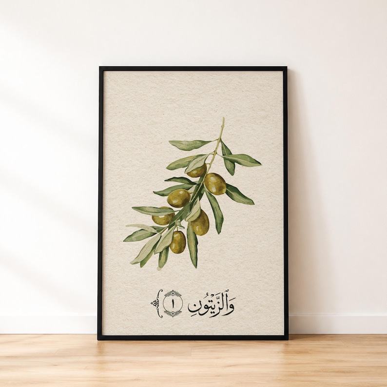 May include: A framed wall art print featuring a botanical illustration of an olive branch with green leaves and olives on a textured beige background. Below the branch, the Arabic text "والزيتون" is written alongside the number one in a circle.