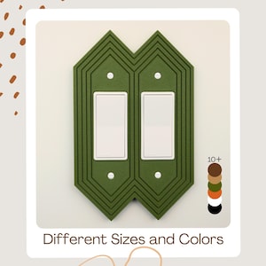 May include: A green decorative double light switch cover with a geometric design. The cover has two white light switches and is surrounded by a green frame. The text "Different Sizes and Colors" is at the bottom.