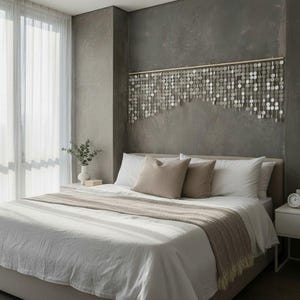 May include: A wall hanging composed of numerous small, circular, reflective silver discs suspended from a horizontal wooden rod. The discs are arranged in multiple vertical strands of varying lengths, creating an uneven, layered, and shimmering effect.