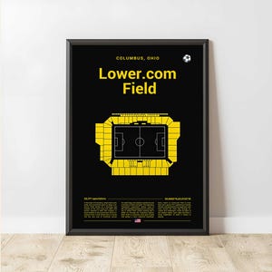 May include: Black framed poster with a yellow graphic of a soccer stadium, labeled "Lower.com Field" in Columbus, Ohio. The poster includes the stadium's seating capacity and coordinates, with a soccer ball icon at the top.