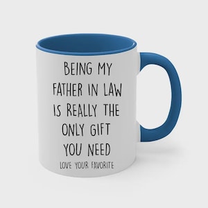 May include: White ceramic mug with a blue interior and handle. The mug features the text "BEING MY FATHER IN LAW IS REALLY THE ONLY GIFT YOU NEED LOVE YOUR FAVORITE" in black lettering.