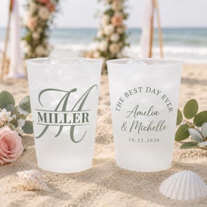 May include: Two frosted plastic cups filled with ice and a clear liquid, likely water or a beverage. One cup has the name "Miller" with a stylized initial "A". The other cup reads "The Best Day Ever" with names and a date. Wedding theme.