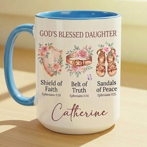 May include: White ceramic mug with a blue handle and interior rim. The mug features the text "GOD'S BLESSED DAUGHTER" and illustrations of a shield, belt, and sandals, with the name "Catherine" at the bottom.