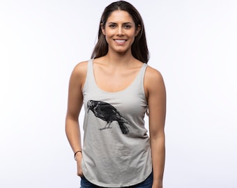 May include: A gray tank top with a black crow graphic print. The tank top has a scoop neck and a relaxed fit.
