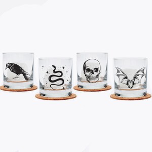 May include: Set of four clear glass tumblers with cork coasters. Each tumbler features a different black and white illustration: a crow, a snake, a skull, and a bat.