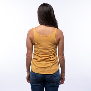 May include: A mustard yellow sleeveless tank top with a scoop neck. The tank top is made of a soft, comfortable fabric and has a relaxed fit.