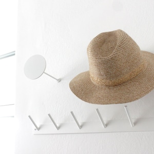 Könnte beinhalten: Ein weißer, an der Wand montierter Kleiderständer mit sechs Haken. Ein Strohhut hängt an einem der Haken.