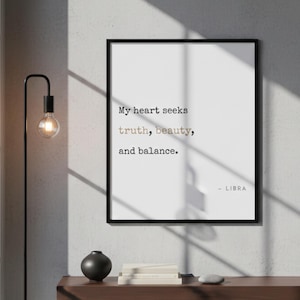 May include: A framed print with the text "My heart seeks truth, beauty, and balance." in a minimalist style. The word "truth" and "beauty" are in a different font. The print is black and white and features the Libra zodiac sign.