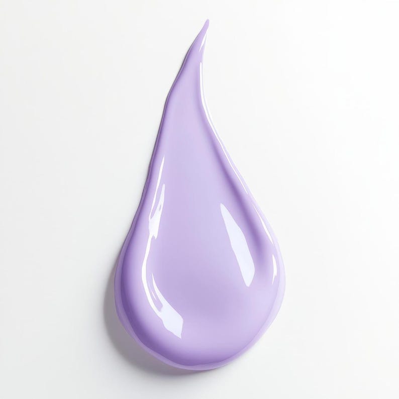 May include: A close-up of a smooth, lavender-colored cosmetic product smear against a white background. The product is in a teardrop shape, with a glossy finish and highlights.