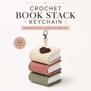 Può includere: Un portachiavi a forma di pila di libri all'uncinetto composto da tre libri sovrapposti color crema, rosa antico e verde salvia con pagine bianche. Un cuore all'uncinetto marrone scuro si trova sul libro superiore. Testo: CROCHET BOOK STACK KEYCHAIN.