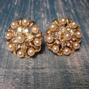 May include: A pair of gold tone earrings with a cluster of faux pearls and rhinestones.