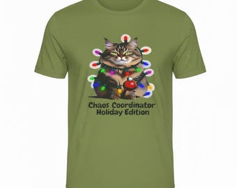 Puede incluir: Camiseta verde oliva con un gato de dibujos animados decorado con luces navideñas y sosteniendo una bola roja. El texto "Chaos Coordinator Holiday Edition" está impreso debajo. La camiseta es de cuello redondo y manga corta.