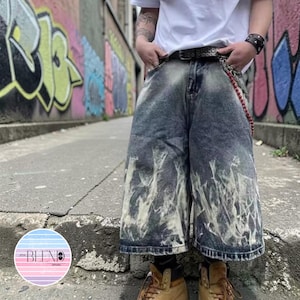 May include: Blue denim shorts with a unique white flame design on the lower portion. The shorts have a wide leg cut and are worn with a black belt and a chain. The shorts are part of the Blend Apparel collection.
