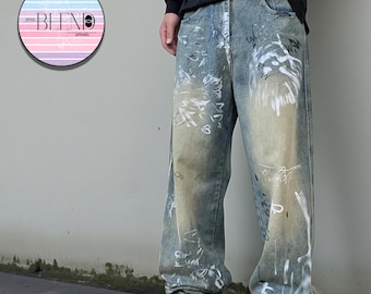 May include: Light blue denim jeans with white paint splatter and graffiti-style markings. The jeans have a relaxed fit and are worn with sneakers. The image includes a circular logo with the text "BLEND" and "APPAREL".