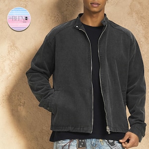May include: A dark gray denim jacket with a zip-up front, a stand-up collar, and two side pockets. The jacket is worn over a black t-shirt. The brand logo is visible in the upper left corner.