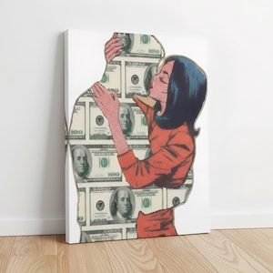 Op de afbeelding: Pop-art canvas print met een vrouw in een rode jurk die een figuur kust gevuld met $100 biljetten. Het kunstwerk heeft een stripboekstijl met gedurfde contouren en een witte achtergrond. Het canvas is gemonteerd op een houten frame.