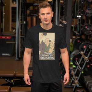 May include: Dark gray t-shirt featuring a vintage Japanese art print. The print depicts a group of men taking a selfie. The text in the image is in Japanese. The shirt is short-sleeved and has a crew neck.