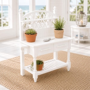 May include: A white potting bench with a lattice back and two drawers. It features a lower shelf and is adorned with potted plants and a small trowel. The bench is set on a woven rug, creating a bright and airy aesthetic.