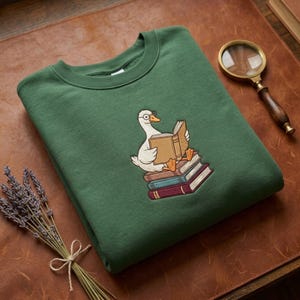 Sweat-shirt brodé personnalisé avec nom et motif oie, pull col rond avec motif canard lecteur, pull pour amoureux des bibliothèques, cadeau idéal pour les femmes, les enseignants et les amoureux des oiseaux.