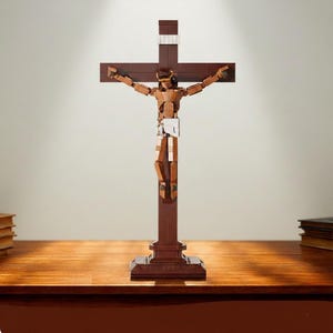May include: A brown crucifix sculpture with a figure of Jesus made from interlocking blocks. The cross is dark brown, and the figure has a light brown torso and limbs. The sculpture is on a wooden surface.