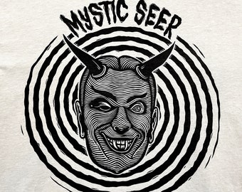 May include: Black and white illustration of a devilish figure with horns and a swirling background. The text "MYSTIC SEER" is above the figure.