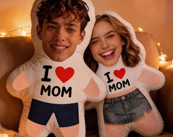 May include: Two custom-printed body pillows with faces, in a seated position. One pillow has a male face, wearing a white shirt with "I ❤️ MOM" and navy blue shorts. The other pillow has a female face, wearing a white shirt with "I ❤️ MOM" and a denim skirt.
