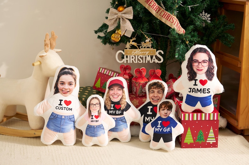 May include: A collection of five custom-shaped plush pillows featuring printed photographs of faces on the upper portion and graphic text including I heart CUSTOM, I heart MY BF, I heart MY GF, and I heart JAMES on the lower torso area.