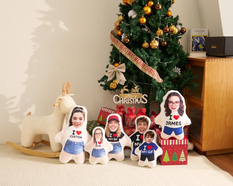 May include: A collection of five custom-shaped plush pillows featuring printed portraits of individuals wearing shirts with the text I heart CUSTOM, I heart MY BF, I heart MY GF, and I heart JAMES, with red heart icons and blue denim shorts.