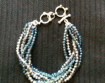 Cuentas de cristal brillantes en azul y gris con un patrón trenzado.