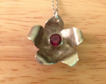 Flor de plata de primera ley con centro de granate facetado