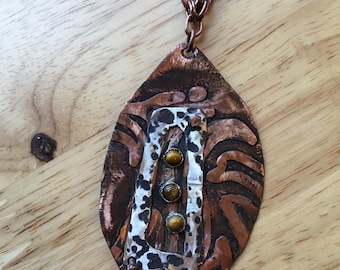 Colgante ovalado de cobre grabado y plata de primera ley martillada con ojos de tigre
