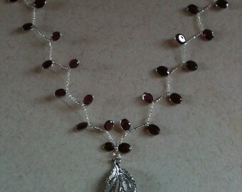 Collar de plata brillante con hojas de granate y delicado colgante de hoja
