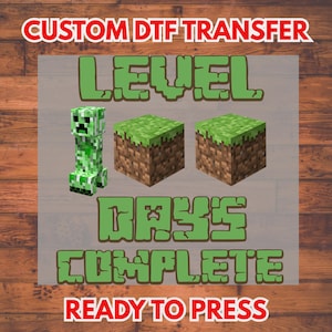 May include: A DTF transfer design featuring a green Creeper character and two grass-topped blocks from the popular video game. The words "LEVEL", "DAYS COMPLETE", and "READY TO PRESS" are also included in the design.
