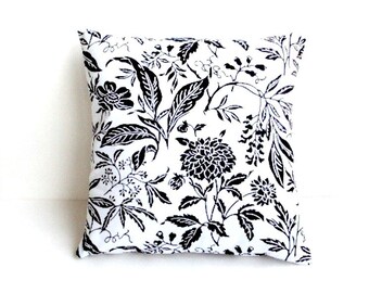 May include: Square throw pillow with a black and white floral pattern. The design features various leaves and flowers in a detailed, botanical style. The pillow is square and appears to be made of fabric.