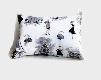 May include: Rectangular decorative pillow with a white background and a black and gray Parisian-themed print. The print includes illustrations of landmarks, fashion figures, and the word "Paris".