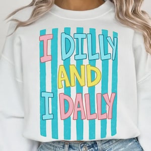 May include: White sweatshirt with the text "I DILLY AND I DALLY" in a colorful design. The text is in pink, yellow, and blue, with blue vertical stripes. A casual, comfortable top.