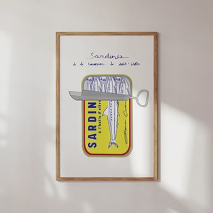 Chic Hand-drawn minimalist kitchen and bar cart print "Sardines" art print poster by KunstbyStephie. A framed print of a yellow sardine can with a silver can opener. The can is labeled 'SARDIN - A L'HUILE D'OLIVE' and has a blue and white illustration of sardines. The text above the can reads 'Sardines de la Conserverie de Dall-Vella'.