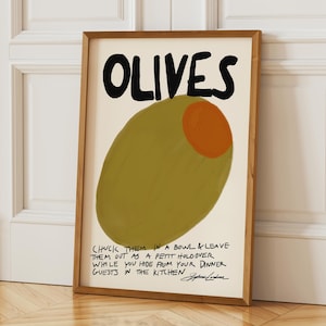 Könnte beinhalten: Ein gerahmter Kunstdruck mit einer großen, stilisierten olive in Olivgrün mit einem orangefarbenen Kern. Der Text OLIVES steht oben, ergänzt durch eine handschriftliche Bildunterschrift unten über das Verstecken vor Gästen.