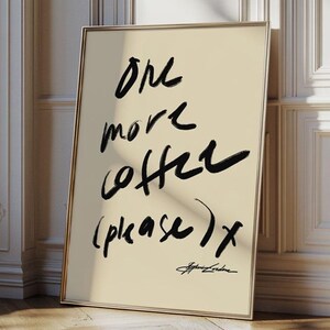 Puede incluir: Una impresi&oacute;n art&iacute;stica enmarcada con el texto "One more coffee (please) x" en trazos de pincel negros sobre un fondo crema. La impresi&oacute;n tiene un marco dorado y est&aacute; apoyada contra una pared blanca con molduras decorativas.