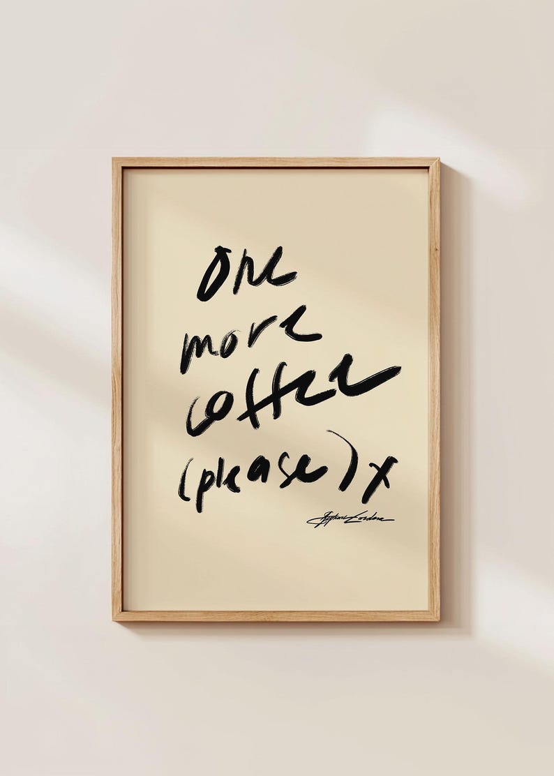 Puede incluir: Impresi&oacute;n art&iacute;stica enmarcada con la frase "One more coffee (please) x" en trazos negros sobre fondo crema. La impresi&oacute;n est&aacute; en un marco de madera clara, adecuada para la decoraci&oacute;n de cocina o comedor.