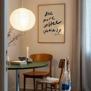 Puede incluir: Un comedor con una mesa redonda verde y dos sillas de madera. Una linterna de papel cuelga sobre la mesa. Un cartel enmarcado con el texto "One more coffee (please) x" est&aacute; en la pared. Una bolsa de mano cuelga en el respaldo de una silla.