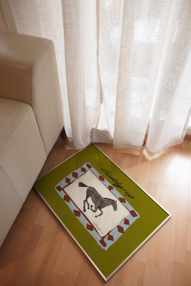 Puede incluir: Una impresi&oacute;n art&iacute;stica enmarcada con una ilustraci&oacute;n de un caballo negro y el texto "Giddy-up". La obra de arte tiene un borde verde y un marco plateado. La impresi&oacute;n se exhibe en un suelo de madera.