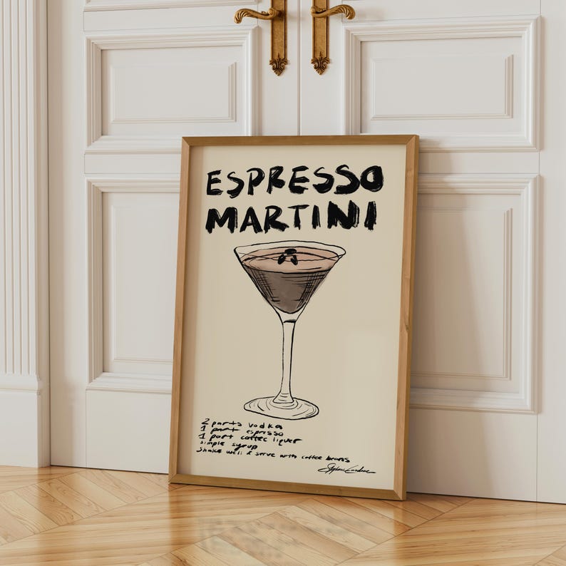 May include: A framed print with an Espresso Martini illustration. The artwork features the words "Espresso Martini" in black. Below the drink illustration are the ingredients and instructions. The frame is a light brown colour.